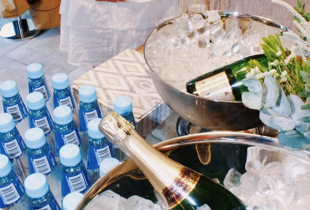 Elegant event setup with champagne bottles in ice buckets, water, and guests.
